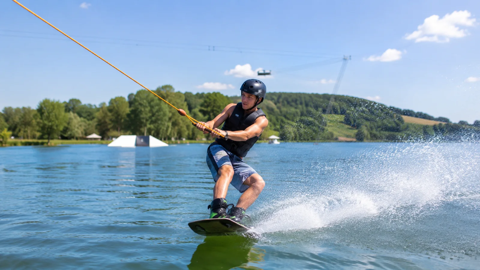 Illustration photoréaliste : débutant en wakeboard tracté par le téléski nautique sur le lac de Caniel