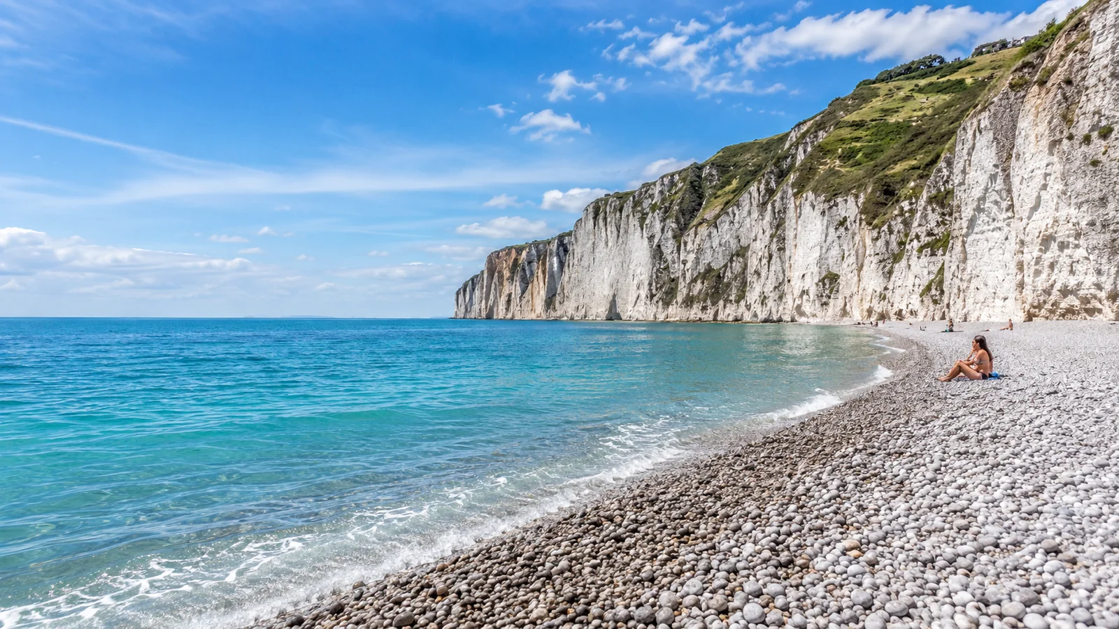 Illustration photoréaliste : vaste plage de galets au pied de hautes falaises blanches avec une mer turquoise sur la Côte d’Albâtre